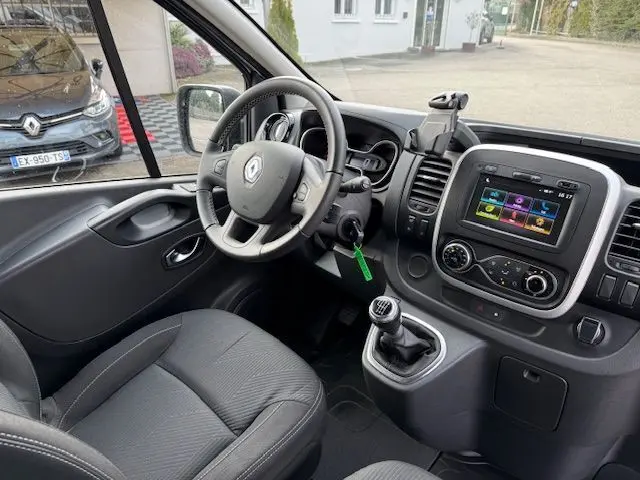 Vue intérieure côté conducteur du Renault Trafic Fourgon gris platine, montrant volant, tableau de bord et écran tactile central.