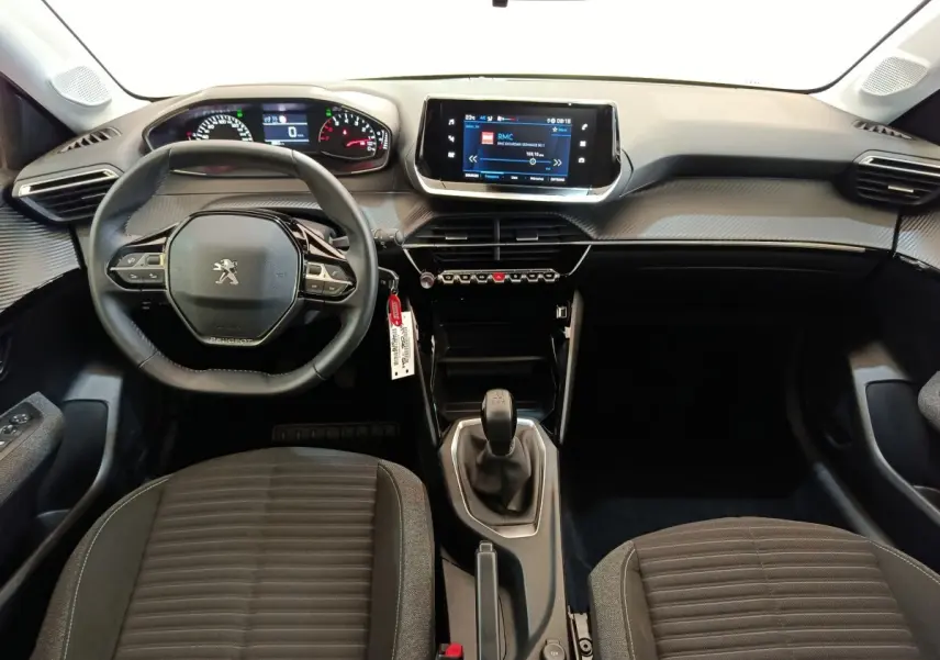 Vue intérieure avant de la Peugeot 208 PureTech 75 Style 2023, tableau de bord noir avec écran tactile central et volant cuir.