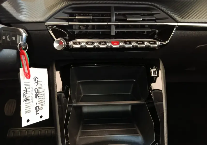 Vue rapprochée du tableau de bord noir de la Peugeot 208 2023 avec commandes et prise USB visible.