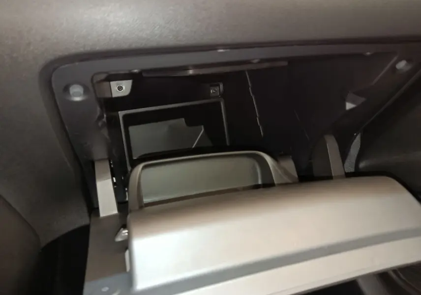 Gros plan intérieur sur la boîte à gants ouverte de la Peugeot 208 PureTech 75 S&S Style 2023, finition noire.