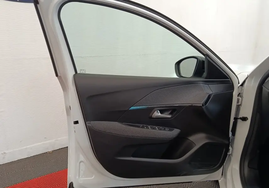 Vue intérieure de la porte avant gauche blanche d'une Peugeot 208 2023 avec garniture noire et détails texturés.