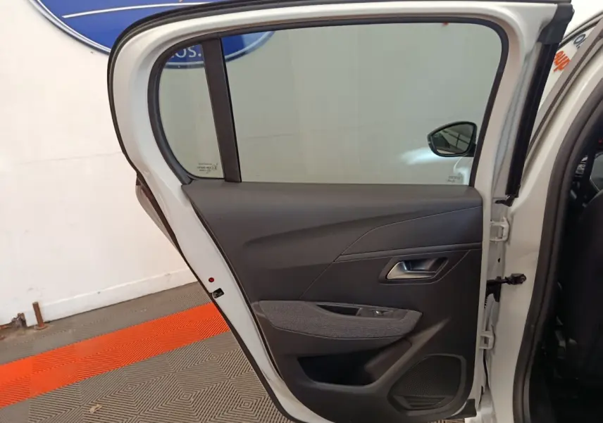 Vue intérieure de la porte arrière droite blanche d'une Peugeot 208 2023, avec garniture noire et tissu gris.