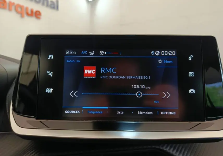 Écran tactile central de la Peugeot 208 blanche PureTech 75 S&S Style affichant la radio RMC à 103,10 MHz.