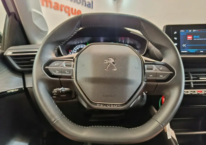 Vue rapprochée du volant cuir multifonctions de la Peugeot 208 PureTech 75 S&S Style avec tableau de bord numérique.