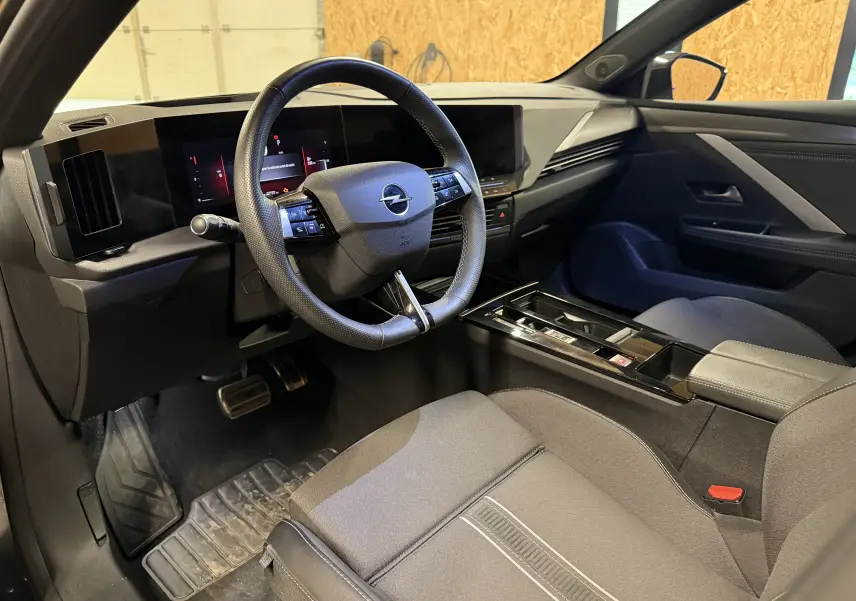 Vue intérieure côté conducteur de l’Opel Astra 2024, volant cuir noir et tableau de bord digital moderne.