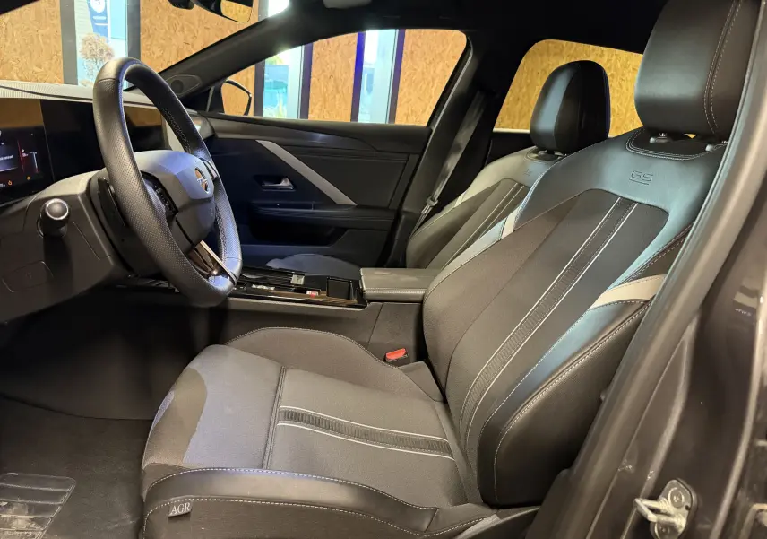 Vue intérieure côté conducteur de l’Opel Astra gris 2024, sièges cuir GS avec surpiqûres blanches et volant cuir.