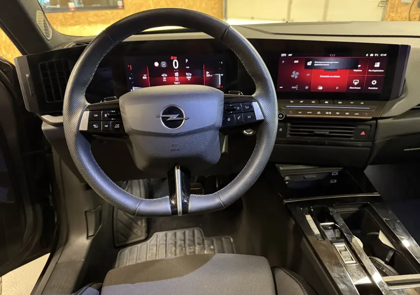 Vue intérieure centrée sur le volant cuir noir et le tableau de bord numérique de l'Opel Astra 2024.
