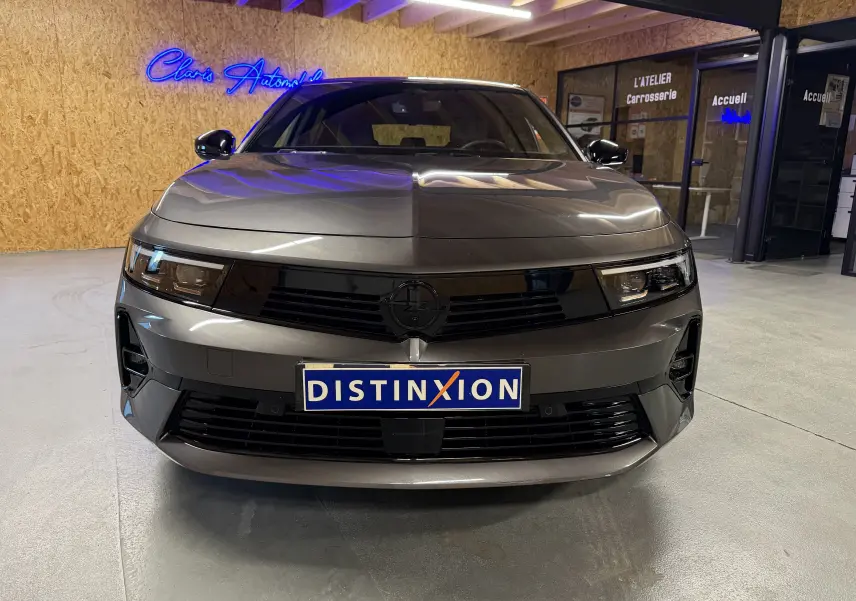 Vue de face d'une Opel Astra 2024 gris métallisé avec calandre noire et phares LED dans un garage.
