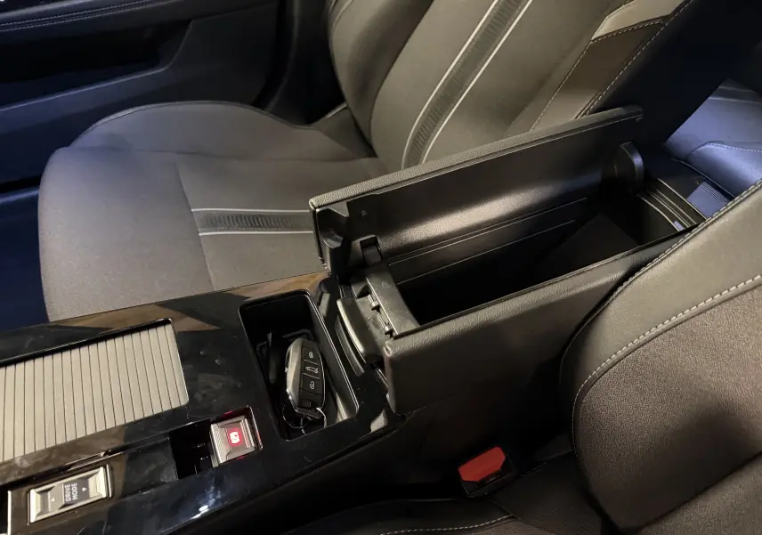 Vue intérieure rapprochée de l'accoudoir central ouvert et de la clé sur la console d'une Opel Astra gris foncé.