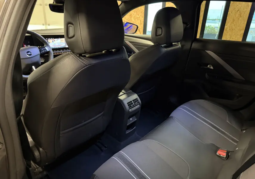 Vue arrière intérieure de l’Opel Astra 2024, sièges noirs en cuir et tissu avec console centrale et ventilation arrière.