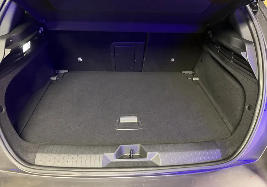 Coffre ouvert de l'Opel Astra gris 2024, vue intérieure montrant un espace de chargement propre et bien éclairé.