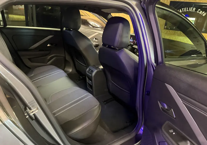 Vue intérieure arrière côté gauche de l’Opel Astra gris 2024, montrant les sièges et la console centrale avec aérateurs.