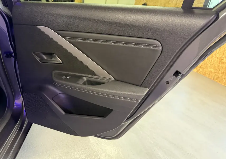 Vue intérieure de la porte arrière droite de l'Opel Astra gris 2024 avec garniture noire et insert argenté.