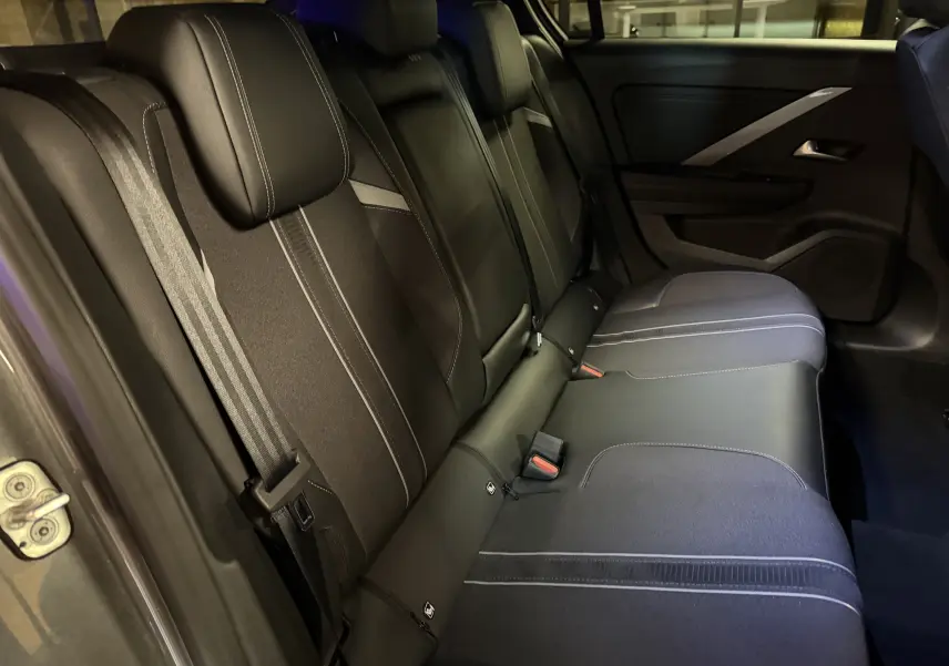 Vue intérieure de la banquette arrière noire de l’Opel Astra 2024 avec ceintures et appuie-têtes visibles côté gauche.