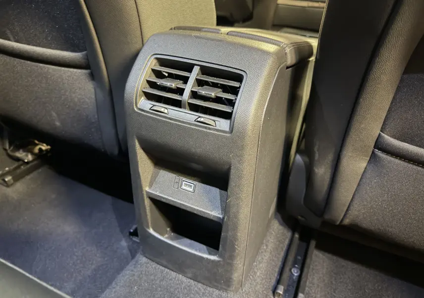 Vue rapprochée de la console arrière noire avec bouches d’aération et port USB dans l’Opel Astra gris 2024.