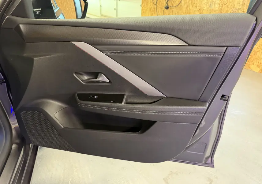Vue intérieure de la porte avant gauche de l'Opel Astra gris, avec garniture noire et surpiqûres contrastées.