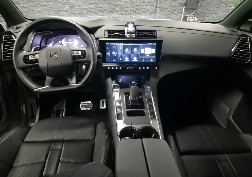 Vue intérieure avant du DS7 Crossback gris, mettant en valeur le volant cuir, l'écran tactile HD et la console centrale moderne.