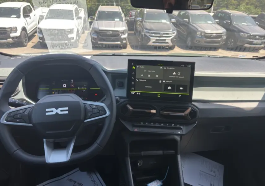 Vue intérieure frontale du tableau de bord du Dacia Duster 2026 kaki avec écran tactile et volant multifonction.