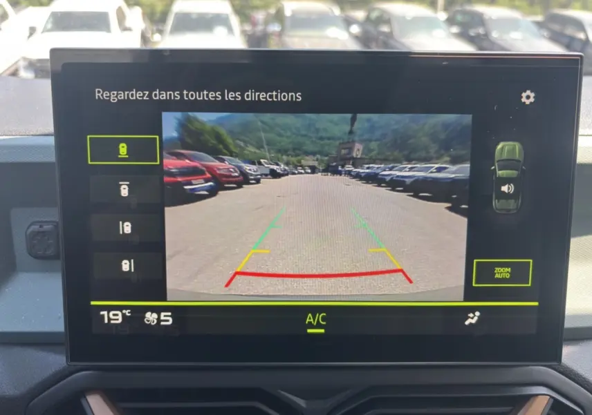 Écran tactile intérieur montrant la caméra de recul du Dacia Duster kaki lichen, vue arrière avec lignes de guidage colorées.