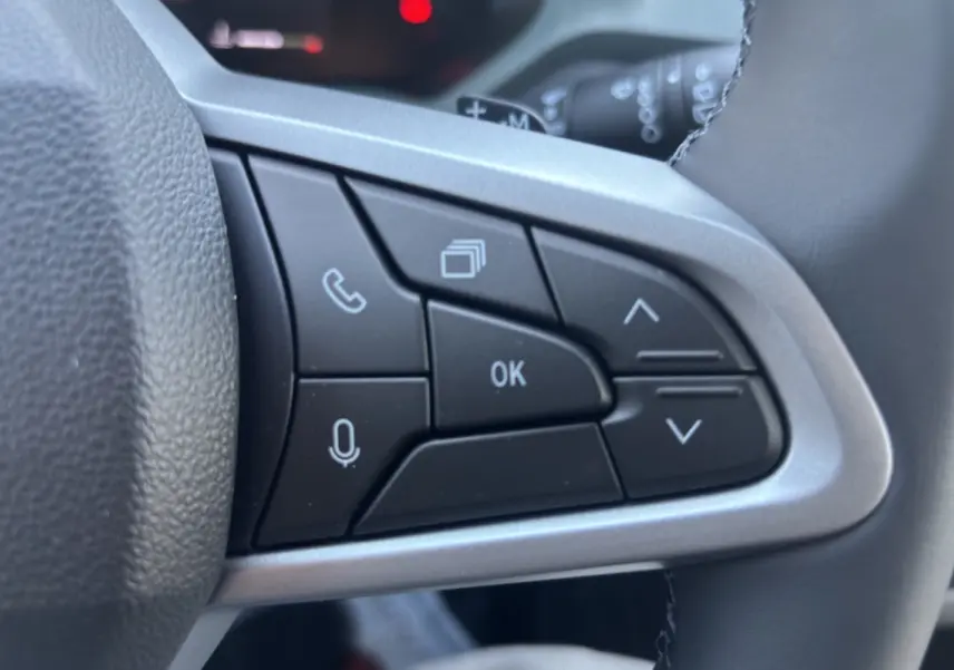 Gros plan sur les commandes multifonctions noires à droite du volant cuir du Dacia Duster 2026.
