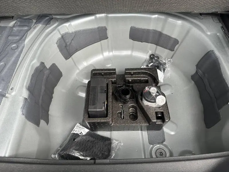 Coffre ouvert montrant le rangement pour roue de secours et outils dans un SEAT Arona gris, vue plongeante intérieure.
