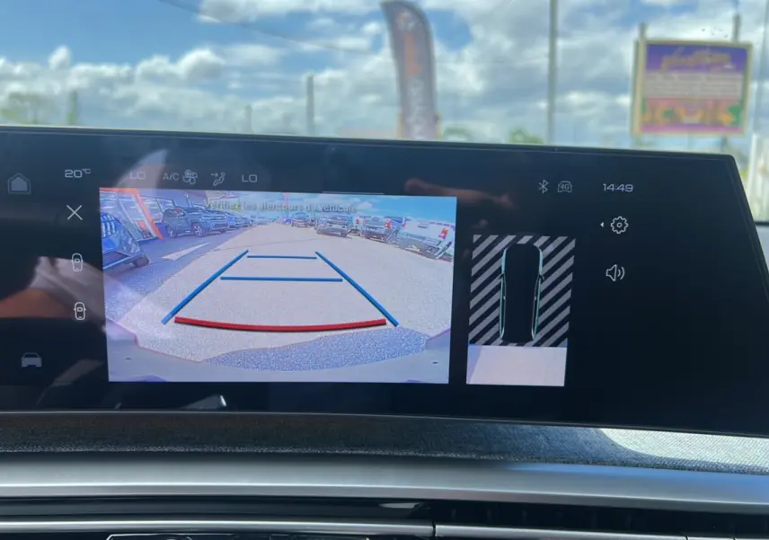 Écran tactile intérieur montrant la caméra de recul et l’aide au stationnement du Peugeot 5008 gris Artense hybride 2025.