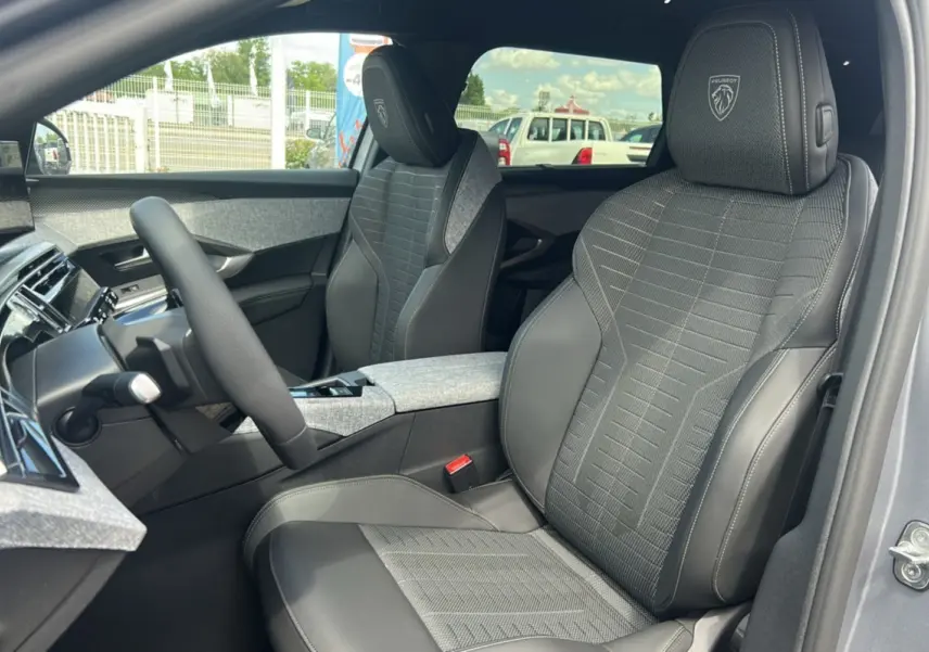 Vue intérieure côté conducteur du Peugeot 5008 Hybrid 145 GT 7 places, sièges tissu et cuir gris avec logo Peugeot brodé.