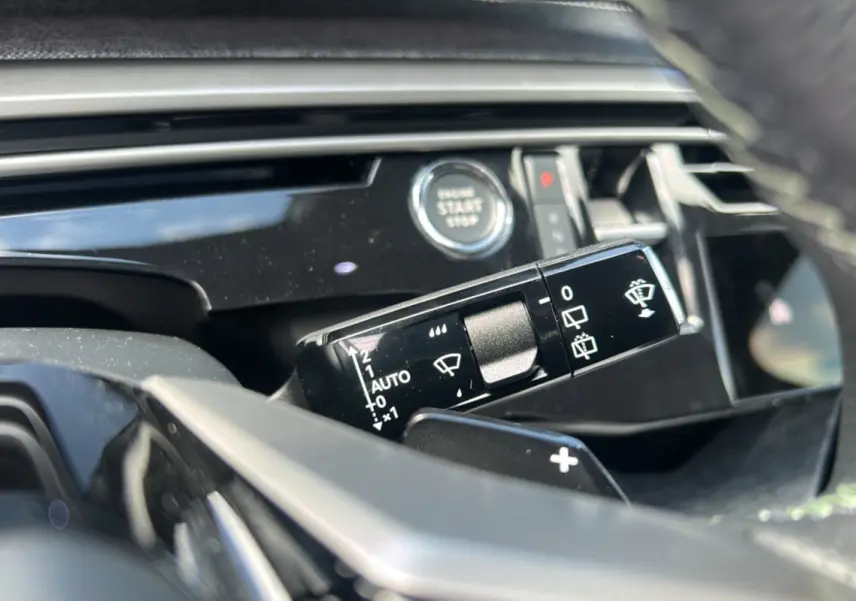 Gros plan sur la commande d’essuie-glace et le bouton start/stop du tableau de bord d’un Peugeot 5008 gris artense 2025.