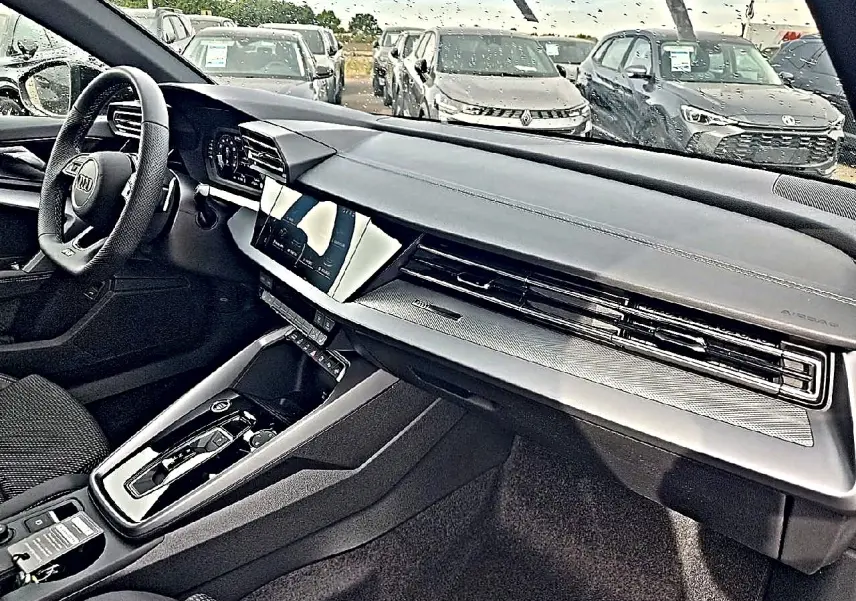 Vue intérieure côté conducteur de l’Audi A3 Sportback 2026 avec tableau de bord noir et écran tactile central.