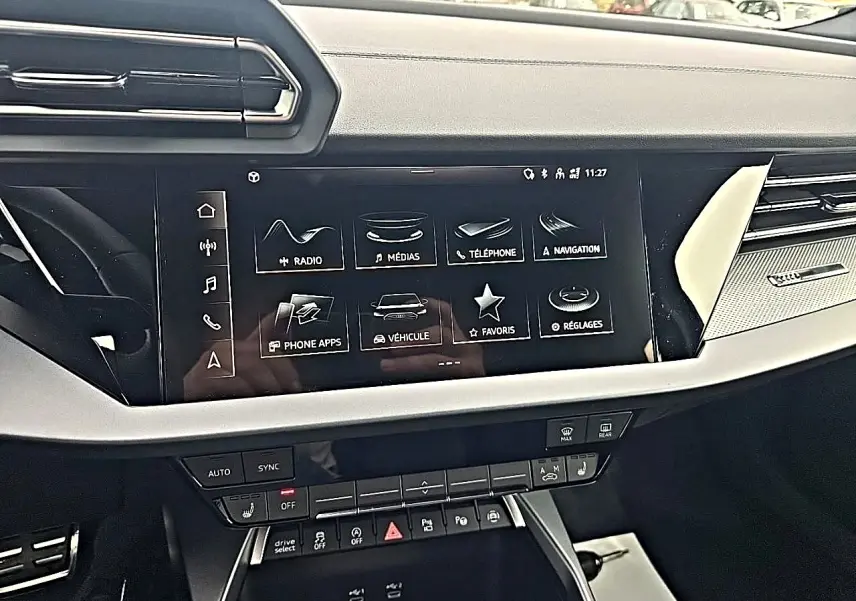Tableau de bord de l'Audi A3 Sportback 2026 avec écran tactile multifonction et commandes climatisation, vue de face intérieure.