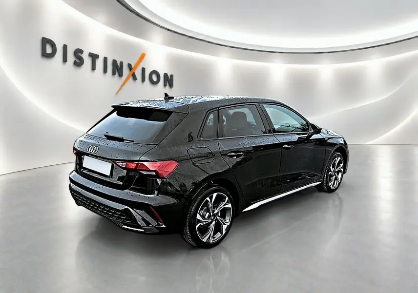 Audi A3 Sportback noir mythos vue 3/4 arrière droit dans un showroom lumineux avec jantes alu distinctives.