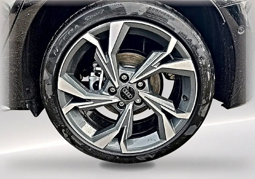 Gros plan sur la jante alu gris graphite de l'Audi A3 Sportback 2026 avec pneu N'Fera Sport humide.