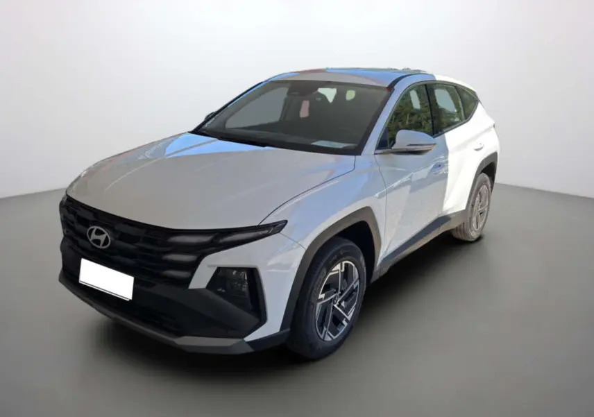Hyundai Tucson blanc atlas en 3/4 avant droit, avec calandre noire distinctive et jantes alu 17 pouces.
