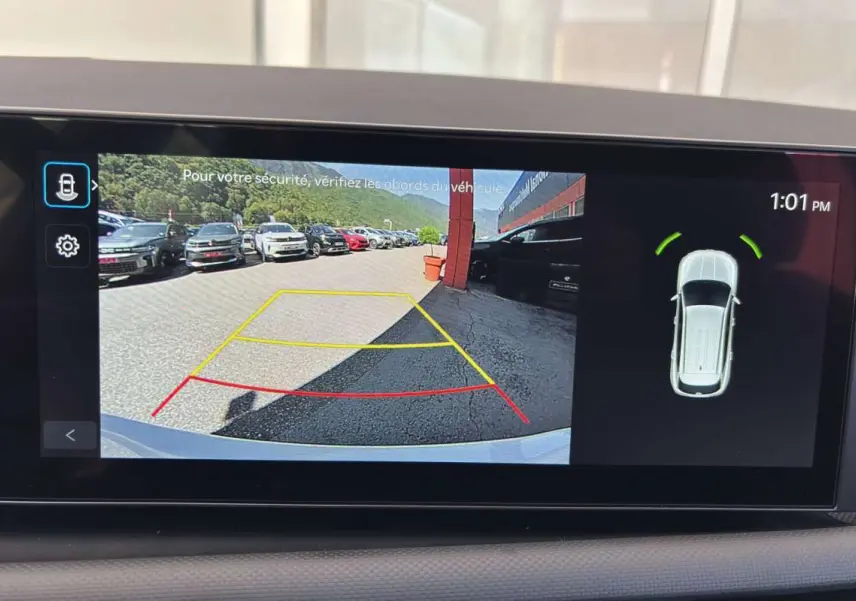Vue écran caméra de recul du Hyundai Tucson blanc atlas, affichant les lignes d'aide au stationnement et l'alerte de proximité arrière.