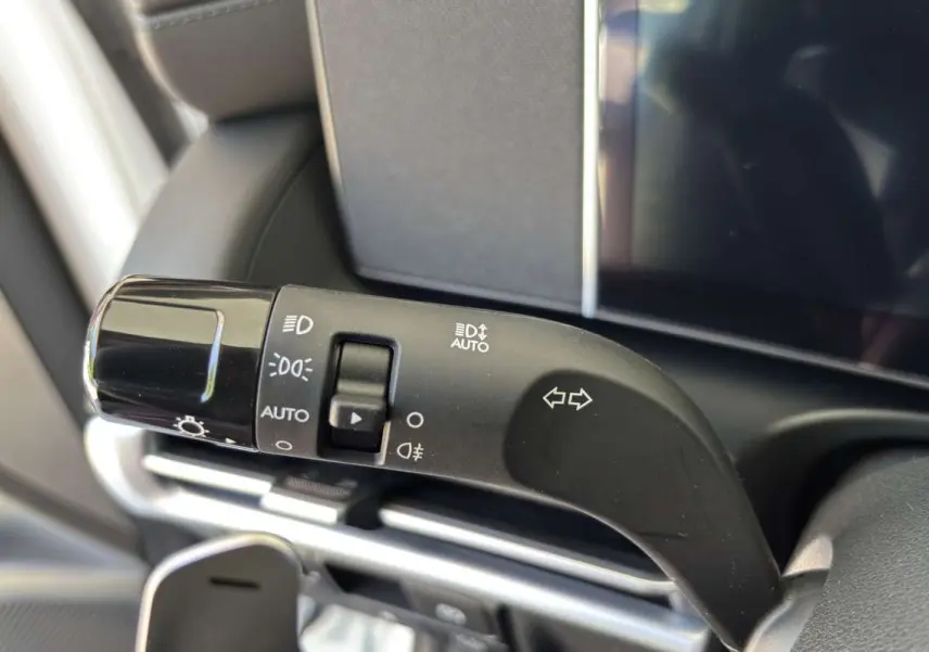 Gros plan sur la commande des feux et clignotants à gauche du volant dans un Hyundai Tucson blanc atlas 2026.