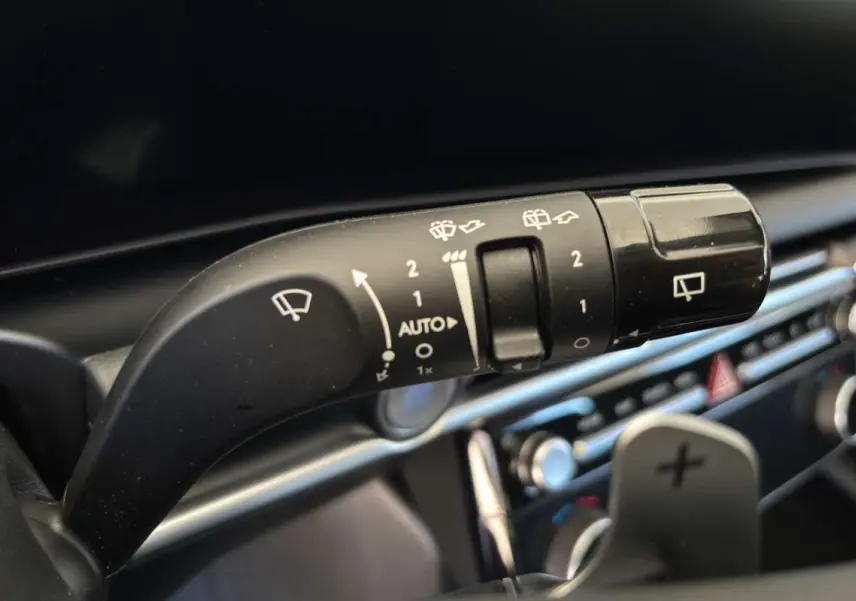 Gros plan sur la commande d’essuie-glace du Hyundai Tucson 1.6 T-GDI HEV 239 blanc atlas, intérieur moderne avec palettes au volant.