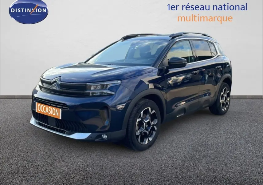 Vue 3/4 avant d'un Citroën C5 Aircross bleu Eclipse Métal avec jantes bi-ton et barres de toit noires.