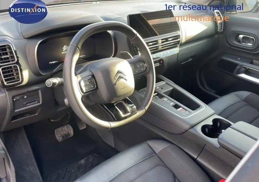 Vue intérieure de la Citroën C5 Aircross 2023, côté conducteur, avec volant multifonction et sellerie noire.
