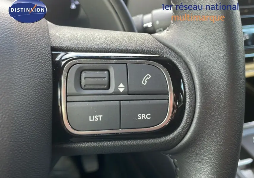 Gros plan sur les commandes noires du volant du Citroën C5 Aircross 2023 bleu Eclipse Metal, avec boutons d’appel et liste.