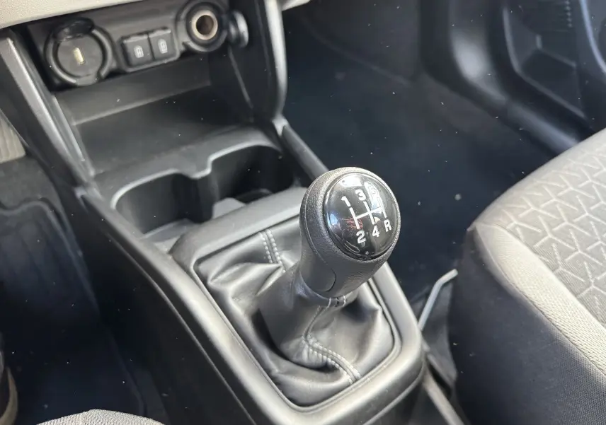 Gros plan sur le levier de vitesses manuel noir de la Suzuki Swift 1.2 Hybrid Privilege 2025, intérieur gris et noir.