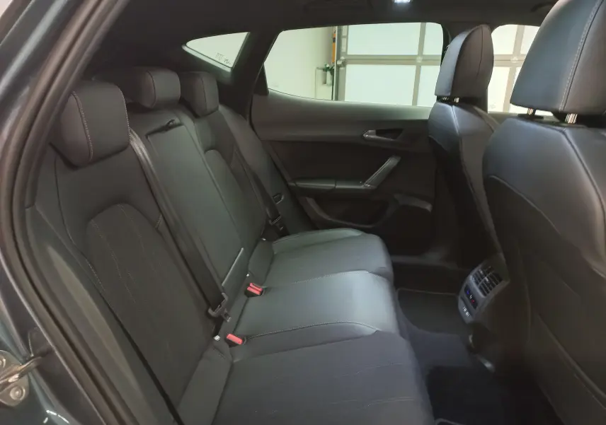 Vue intérieure côté gauche des sièges arrière en cuir noir du CUPRA Formentor 1.5 EHybrid 2025 avec ceinture rouge visible.
