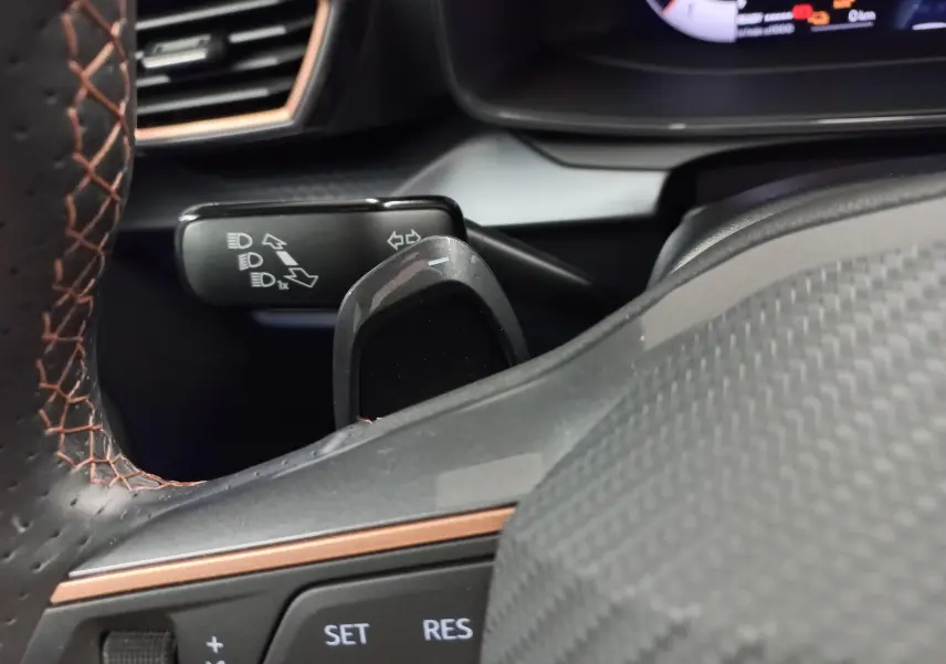 Détail du commodo des clignotants et du volant en cuir noir avec surpiqûres cuivrées dans l'habitacle du CUPRA Formentor hybride.