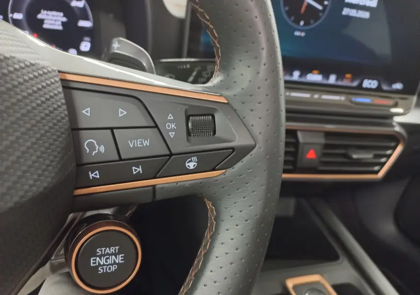 Gros plan sur le volant perforé et les commandes du CUPRA Formentor 1.5 EHybrid 2025 avec surpiqûres cuivre et bouton start/stop.