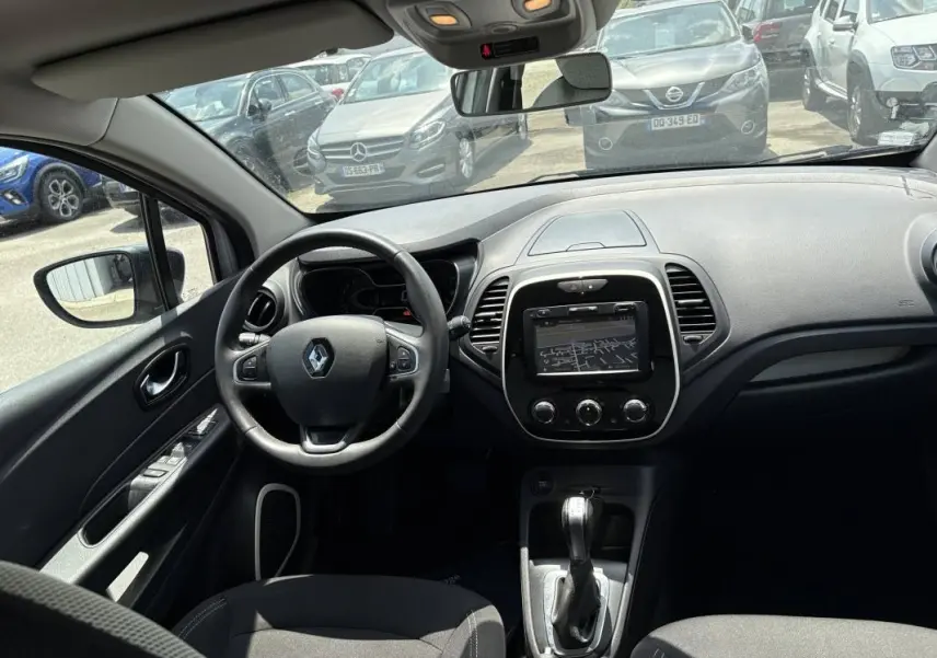 Vue intérieure avant du Renault Captur gris 2017, montrant le volant multifonction et l’écran tactile central.