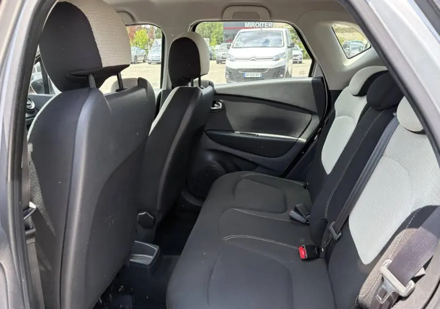 Vue intérieure arrière côté gauche du Renault Captur gris, montrant les sièges arrière en tissu bicolore noir et gris.