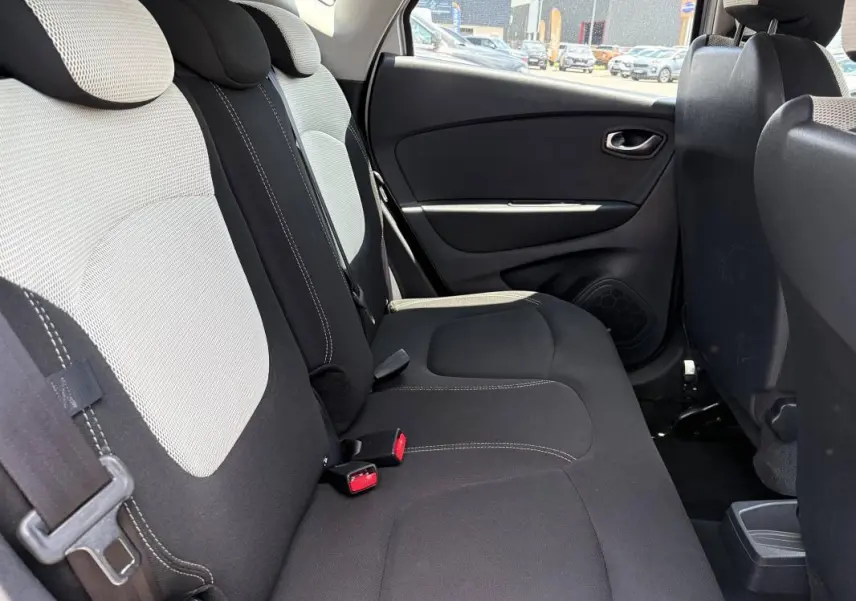 Vue intérieure côté droit des sièges arrière noirs et gris du Renault Captur I, avec ceintures et garnitures visibles.