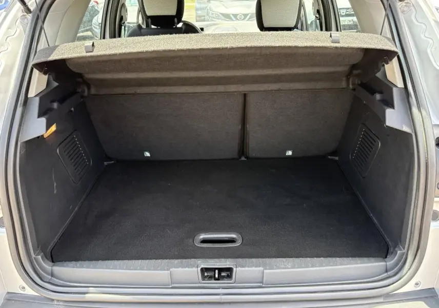 Coffre ouvert vu de l'arrière d'un Renault Captur gris, montrant l'espace de chargement et la tablette cache-bagages relevée.