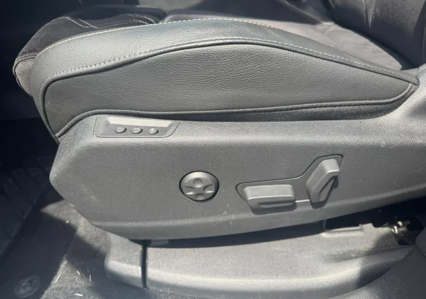 Détail du côté gauche du siège avant en cuir noir avec commandes électriques sur DS7 Hybride Rechargeable 2024.