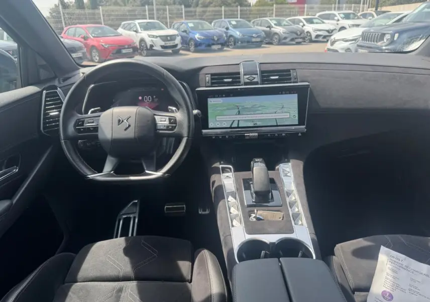 Vue intérieure avant du DS7 2024 hybride rechargeable, mettant en valeur le volant DS, l'écran tactile large et la console centrale en alcantara.