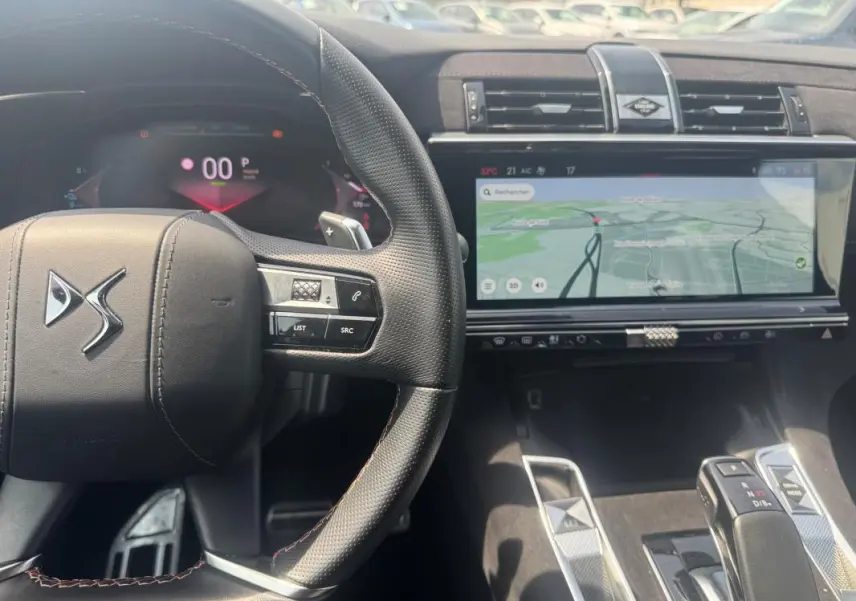 Vue intérieure centrée sur le volant DS et l'écran tactile du tableau de bord du DS7 hybride gris foncé 2024.